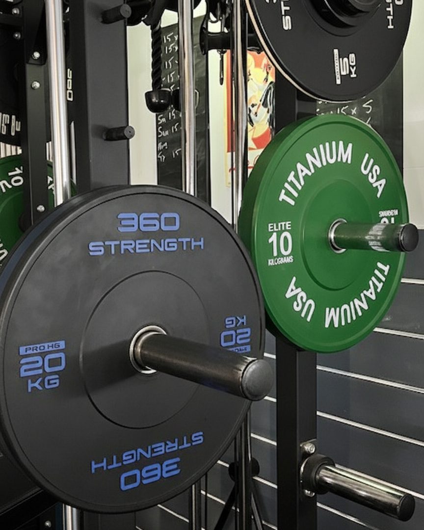 Bumper plates loaded on the rack in the private studio, with a client's program chalked on the board behind